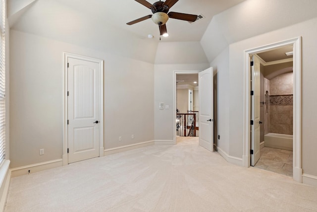 unfurnished bedroom featuring connected bathroom, light carpet, lofted ceiling, and ceiling fan