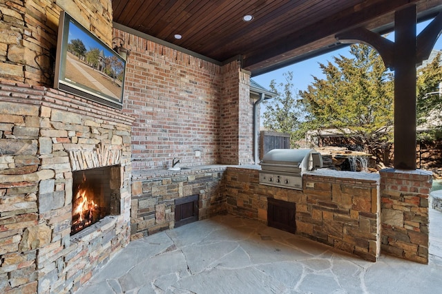 view of patio featuring an outdoor kitchen, area for grilling, and an outdoor stone fireplace