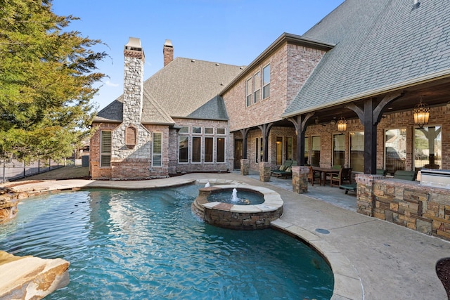 view of pool with an in ground hot tub, exterior kitchen, and a patio