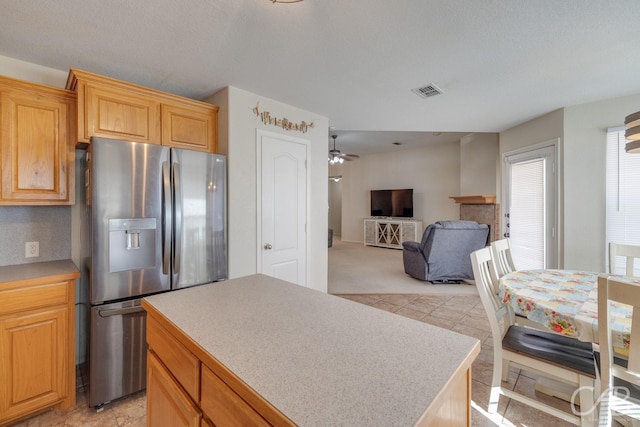 kitchen with ceiling fan, stainless steel fridge, and a kitchen island