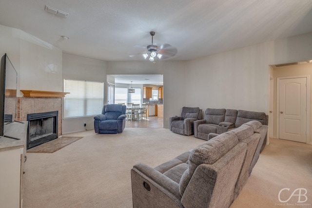 carpeted living room with ceiling fan and a fireplace