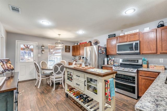 kitchen featuring appliances with stainless steel finishes, decorative light fixtures, and dark hardwood / wood-style flooring