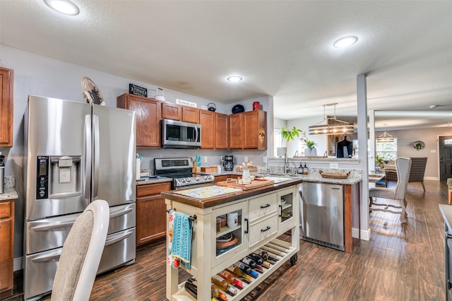 kitchen featuring pendant lighting, sink, appliances with stainless steel finishes, dark hardwood / wood-style floors, and a textured ceiling