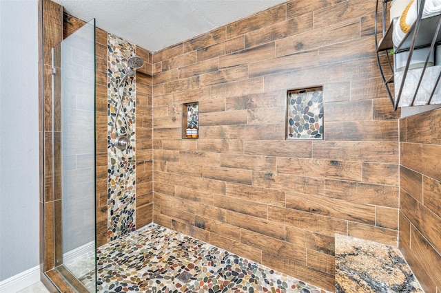 bathroom with a tile shower and a textured ceiling