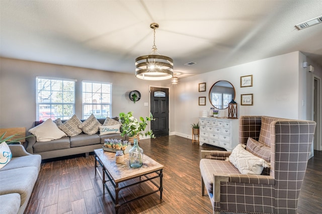 living room with dark wood-type flooring and a chandelier