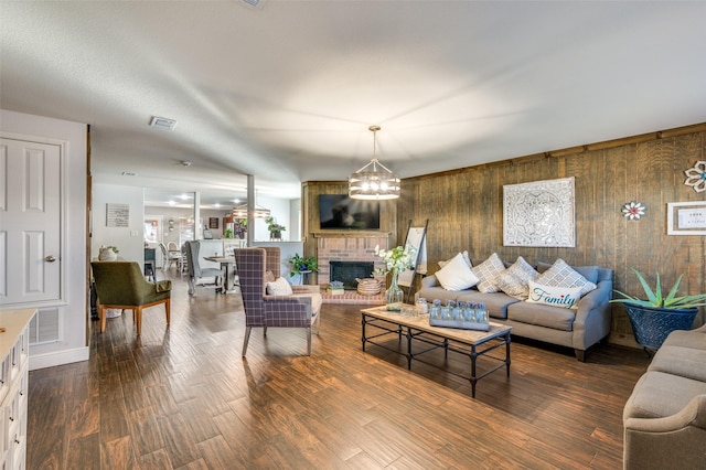 living room featuring a chandelier, hardwood / wood-style floors, a fireplace, and wood walls