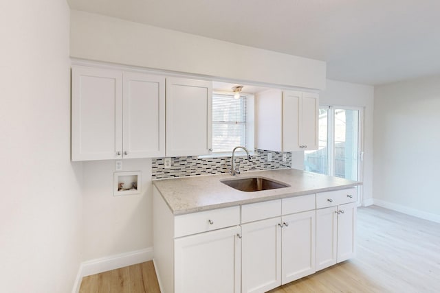 kitchen with sink, white cabinets, decorative backsplash, a healthy amount of sunlight, and light wood-type flooring