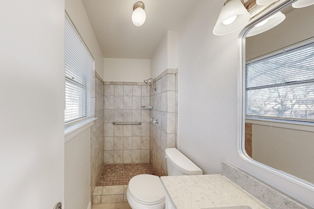 bathroom with a tile shower, vanity, and toilet