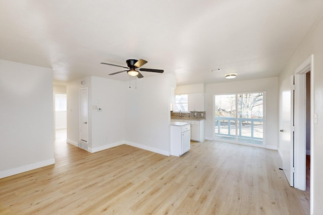 unfurnished living room with sink, light hardwood / wood-style flooring, and ceiling fan