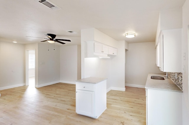 kitchen featuring ceiling fan, white cabinetry, backsplash, light stone counters, and light wood-type flooring