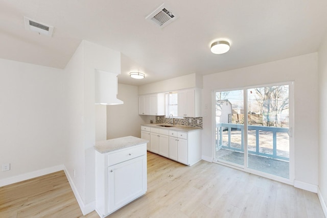 kitchen with sink, light hardwood / wood-style flooring, white cabinets, and decorative backsplash