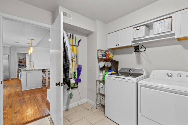 laundry area with sink, washer and dryer, and light wood-type flooring