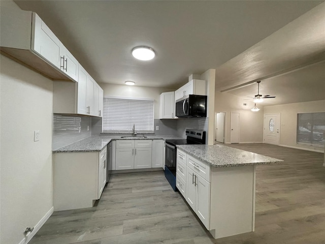 kitchen with stainless steel appliances, white cabinetry, light stone countertops, and sink