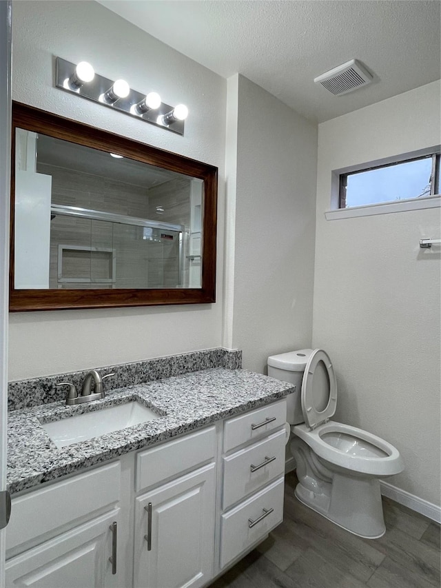 bathroom with vanity, toilet, an enclosed shower, and a textured ceiling