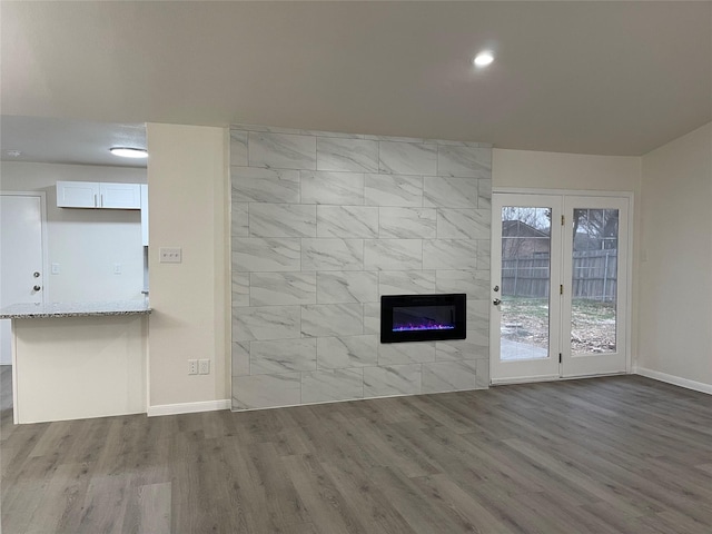 unfurnished living room with a tile fireplace and wood-type flooring