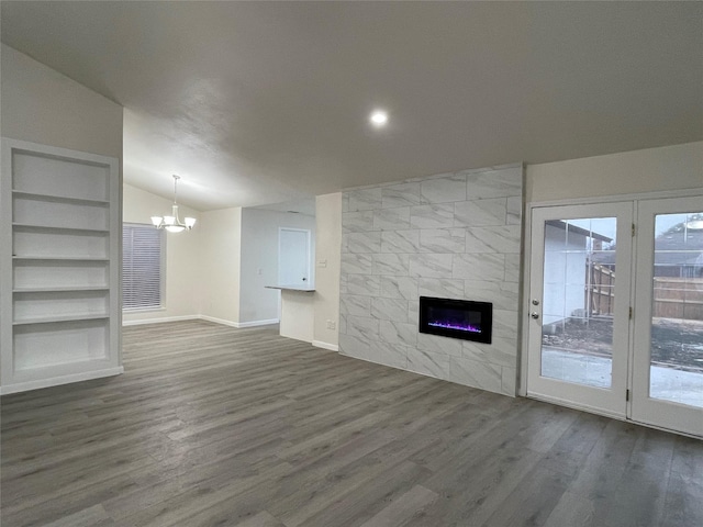 unfurnished living room featuring dark wood-type flooring, a chandelier, vaulted ceiling, built in features, and a tile fireplace