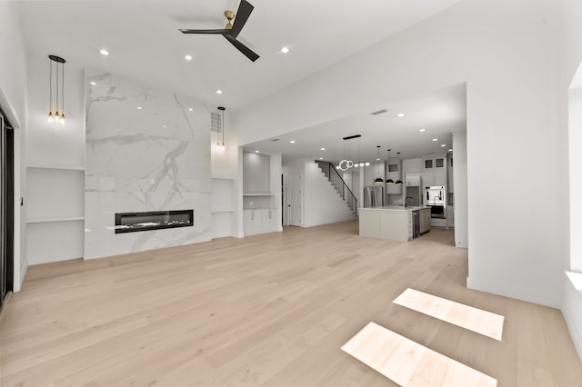 unfurnished living room featuring light hardwood / wood-style flooring, a premium fireplace, and ceiling fan