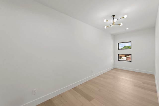 unfurnished room featuring a chandelier and light hardwood / wood-style floors