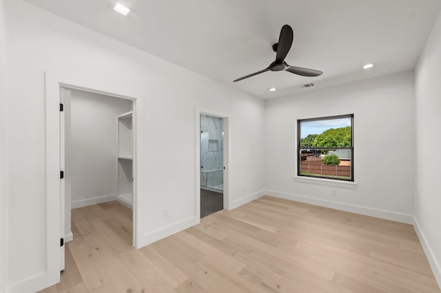 unfurnished bedroom featuring connected bathroom, a spacious closet, light hardwood / wood-style floors, and ceiling fan