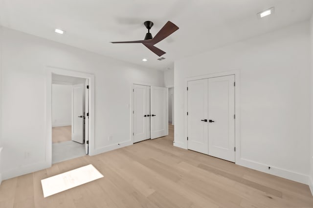 unfurnished bedroom featuring multiple closets, ceiling fan, connected bathroom, and light wood-type flooring