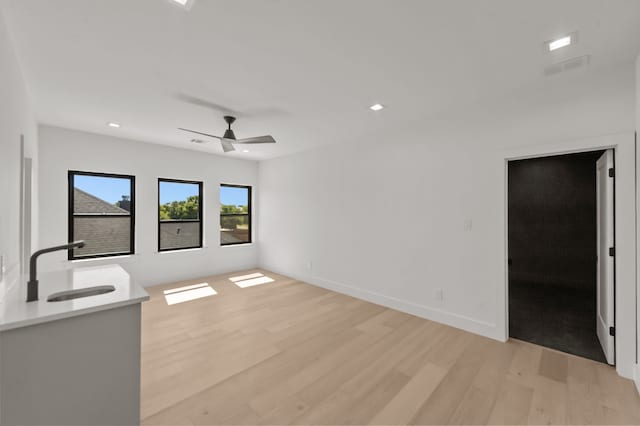 unfurnished living room featuring sink, light hardwood / wood-style floors, and ceiling fan