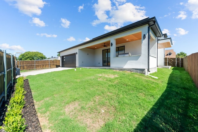 rear view of house with a garage, a lawn, and ceiling fan