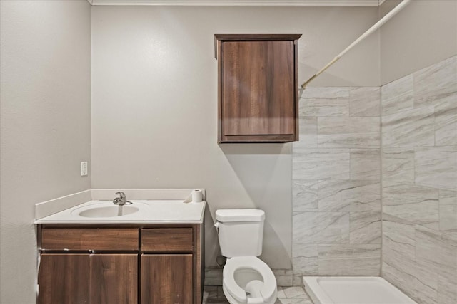 bathroom with vanity, toilet, and a tile shower