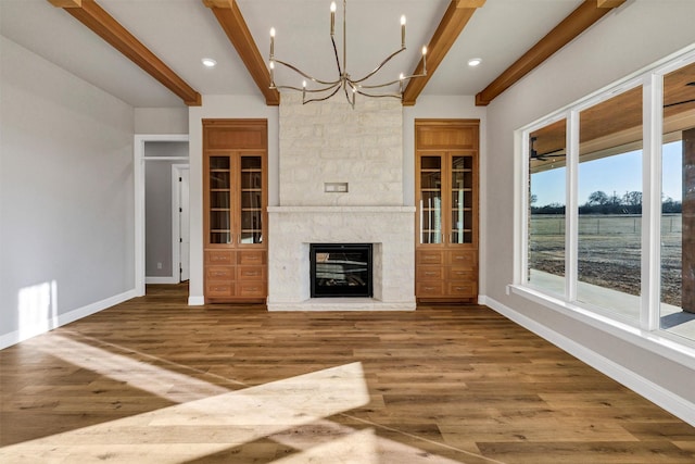 unfurnished living room with wood-type flooring, a high end fireplace, and beamed ceiling