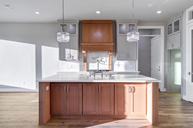 kitchen featuring a large island, backsplash, decorative light fixtures, and wood-type flooring