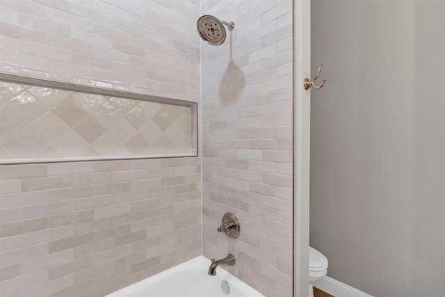 bathroom with toilet and tiled shower / bath combo