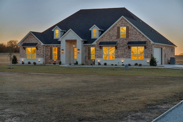 view of front of house featuring central AC unit, a garage, and a lawn