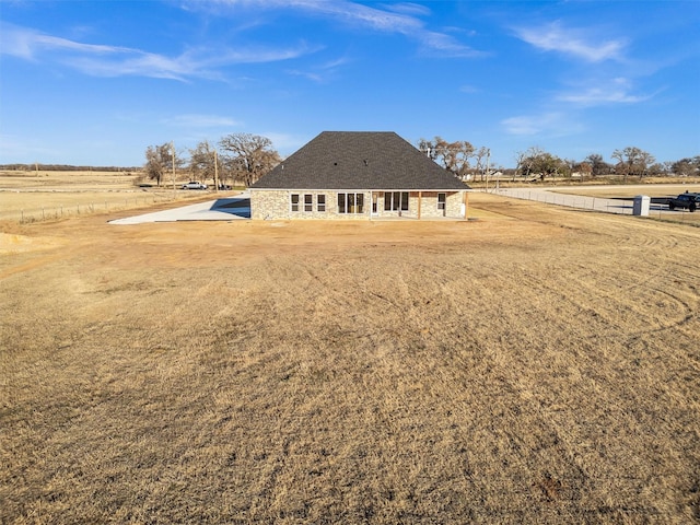 back of house with a rural view and a yard