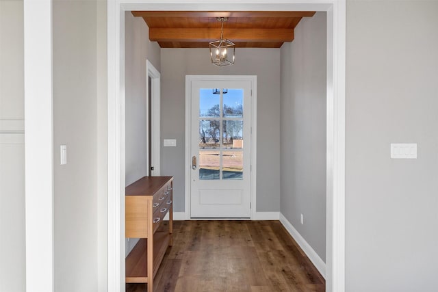 doorway to outside with dark hardwood / wood-style flooring, an inviting chandelier, wood ceiling, and beam ceiling