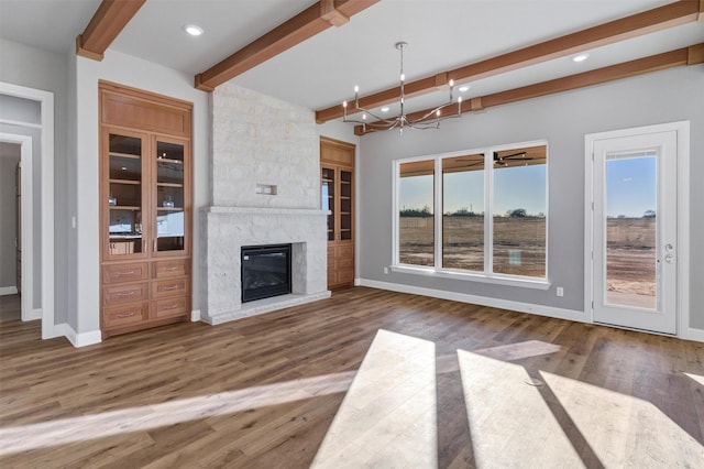 unfurnished living room with hardwood / wood-style flooring, a high end fireplace, beam ceiling, and a notable chandelier