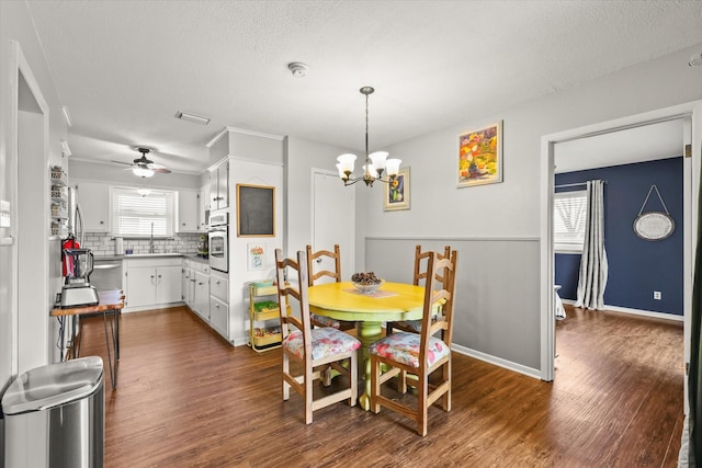 dining space with sink, ceiling fan with notable chandelier, a textured ceiling, and dark hardwood / wood-style flooring