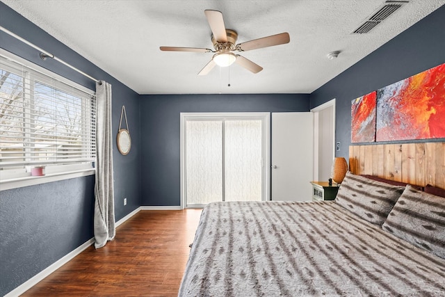 unfurnished bedroom with ceiling fan, dark wood-type flooring, a closet, and a textured ceiling