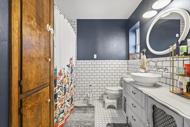 bathroom featuring tile patterned floors, toilet, tile walls, and vanity