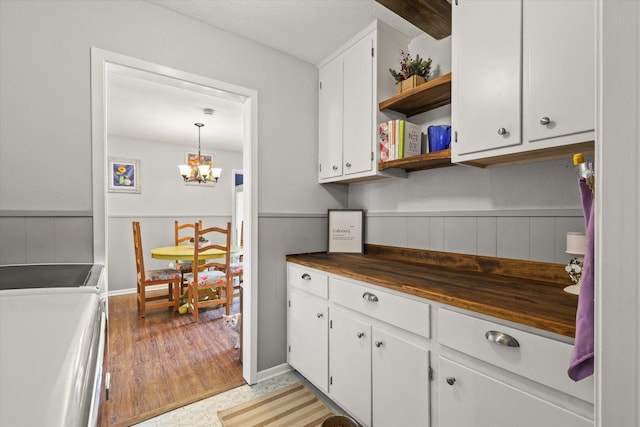 kitchen with white cabinets, a chandelier, hanging light fixtures, washer and clothes dryer, and light wood-type flooring