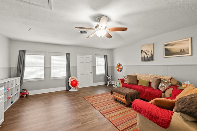 living room featuring ceiling fan, dark hardwood / wood-style floors, and a textured ceiling