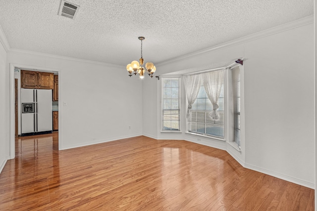 unfurnished dining area featuring a textured ceiling, ornamental molding, a chandelier, and light wood-type flooring