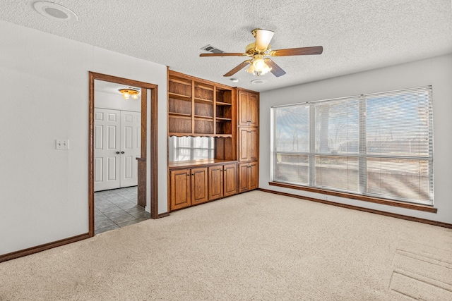 unfurnished living room featuring ceiling fan, light colored carpet, and a textured ceiling