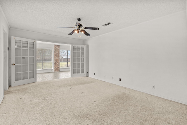 carpeted spare room featuring ceiling fan, ornamental molding, french doors, and a textured ceiling