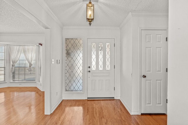 foyer entrance with ornamental molding, light hardwood / wood-style flooring, and a textured ceiling