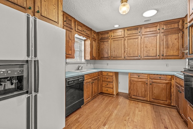 kitchen featuring sink, light hardwood / wood-style flooring, black appliances, and a textured ceiling