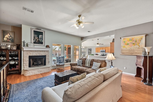 living room with a fireplace, light hardwood / wood-style floors, and ceiling fan