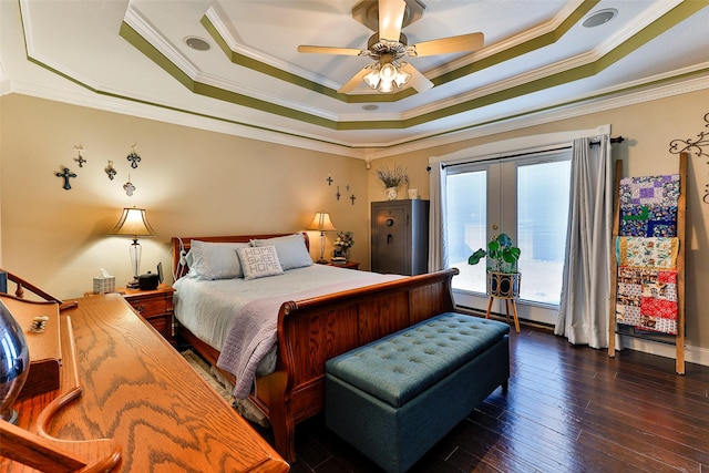 bedroom featuring a tray ceiling, dark wood-type flooring, ornamental molding, and french doors