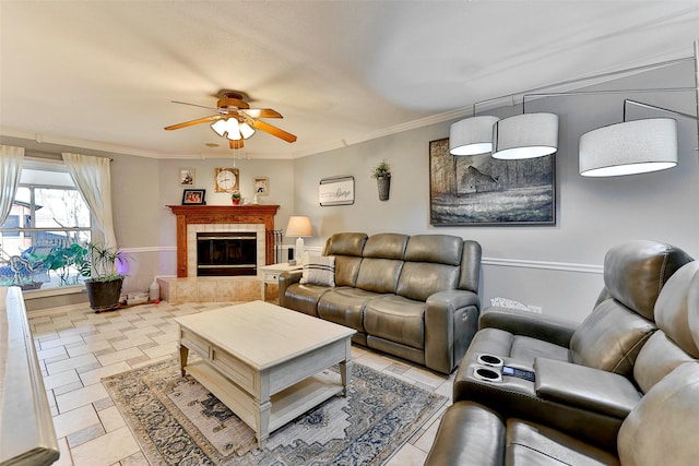 living room featuring a tiled fireplace, crown molding, and ceiling fan