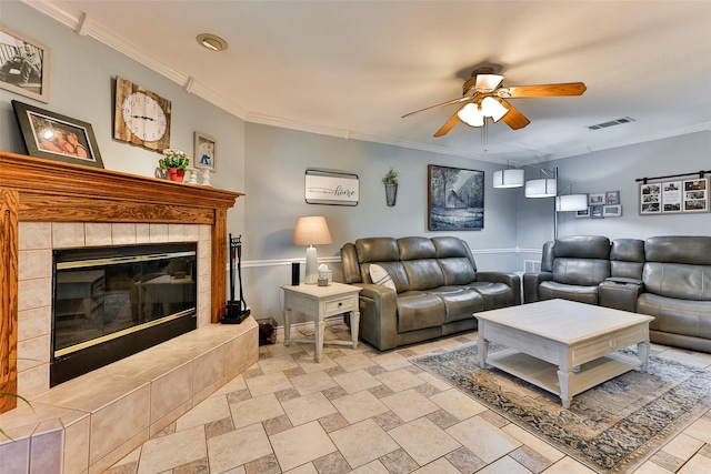 living room featuring ceiling fan, ornamental molding, and a tile fireplace