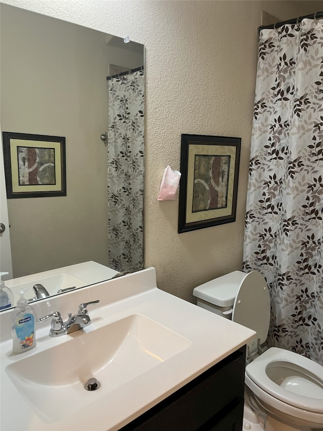 bathroom featuring vanity, curtained shower, and toilet