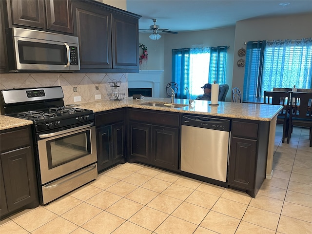 kitchen with sink, backsplash, stainless steel appliances, light tile patterned flooring, and kitchen peninsula